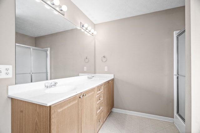 bathroom with an enclosed shower, vanity, and a textured ceiling