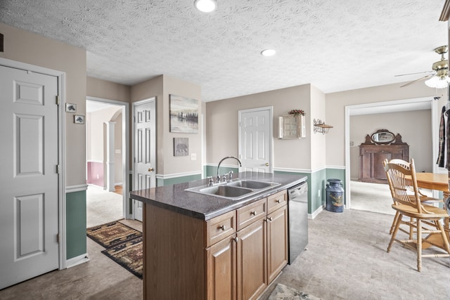 kitchen featuring dishwasher, a textured ceiling, sink, a center island with sink, and ceiling fan