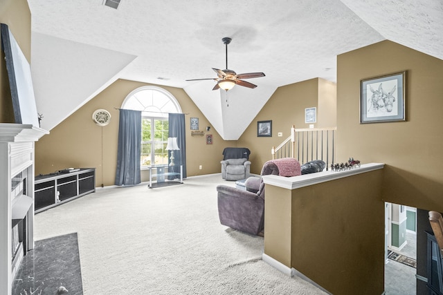 living room with lofted ceiling, ceiling fan, carpet flooring, and a textured ceiling