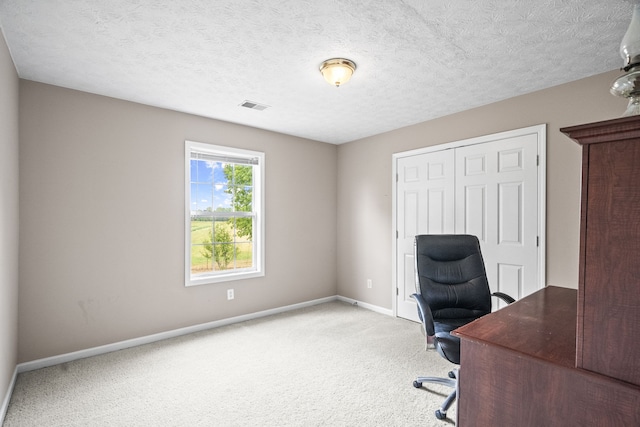 unfurnished office featuring a textured ceiling and light colored carpet