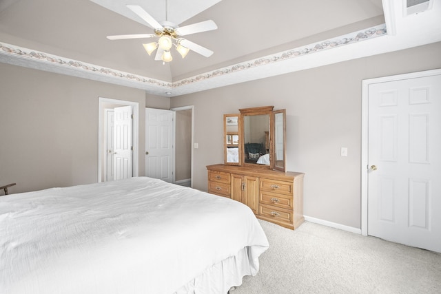 bedroom with ceiling fan, light colored carpet, and a raised ceiling