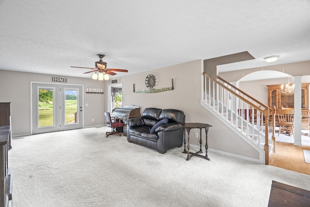 living room with ceiling fan with notable chandelier, a textured ceiling, and carpet flooring