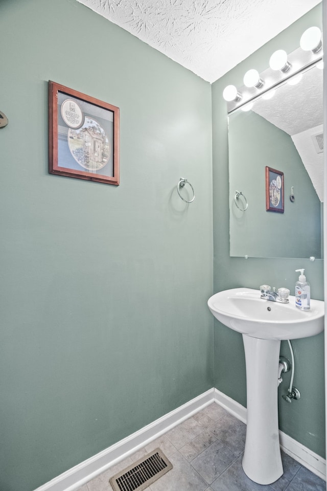 bathroom featuring a textured ceiling and tile patterned floors