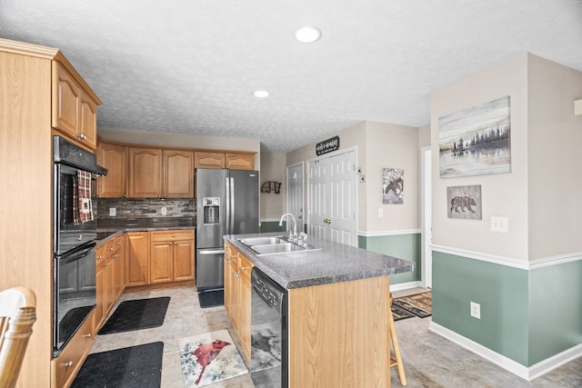 kitchen with a kitchen island with sink, a breakfast bar area, sink, decorative backsplash, and black appliances