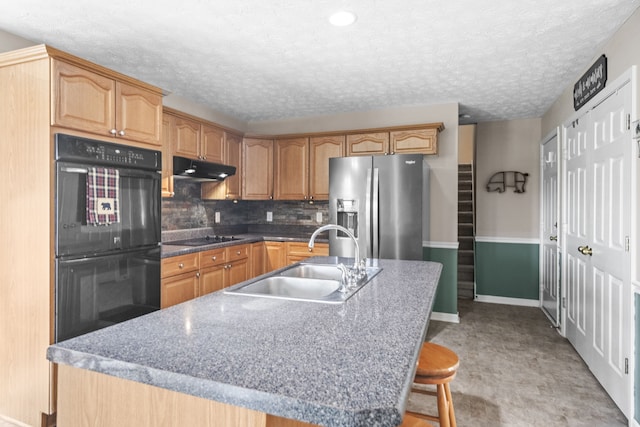 kitchen with a kitchen island with sink, sink, a kitchen breakfast bar, decorative backsplash, and black appliances