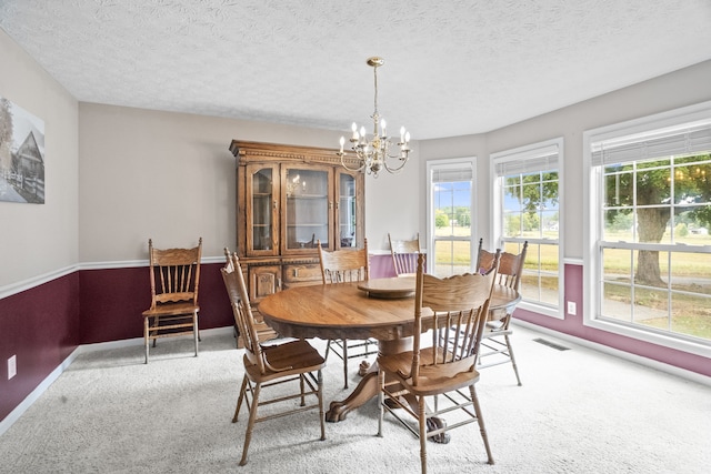 dining room featuring an inviting chandelier, light colored carpet, and a textured ceiling