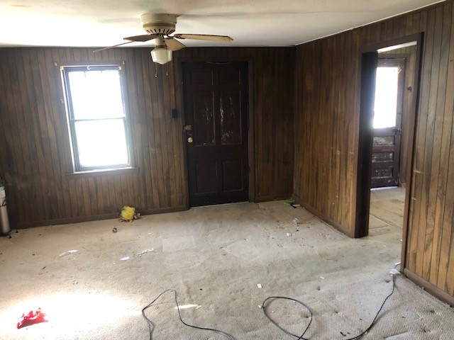 empty room with ceiling fan and wood walls