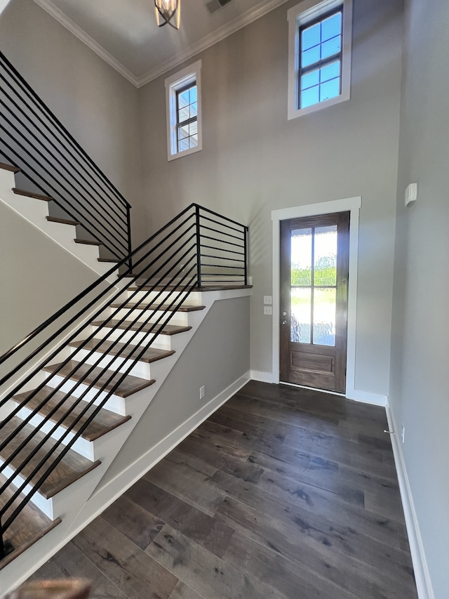 foyer entrance with a towering ceiling, dark hardwood / wood-style floors, and crown molding