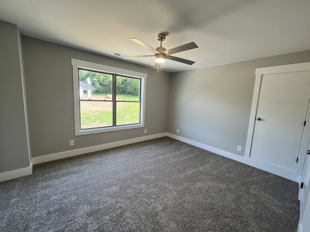 unfurnished room featuring ceiling fan and dark carpet