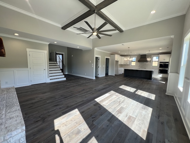 unfurnished living room featuring ornamental molding, ceiling fan with notable chandelier, and dark hardwood / wood-style flooring