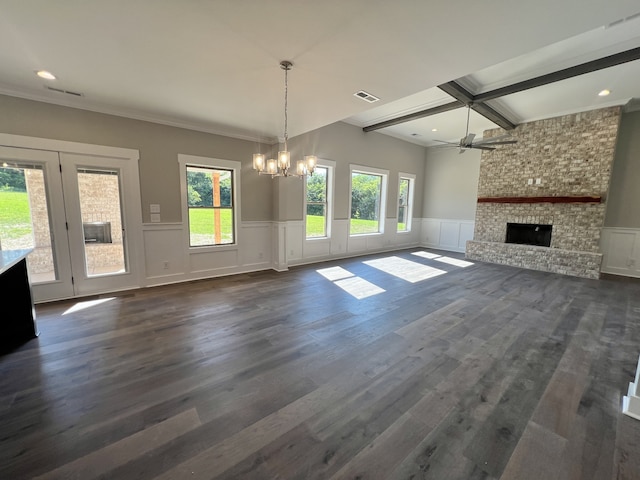 unfurnished living room featuring a healthy amount of sunlight, ceiling fan with notable chandelier, a stone fireplace, and dark hardwood / wood-style flooring