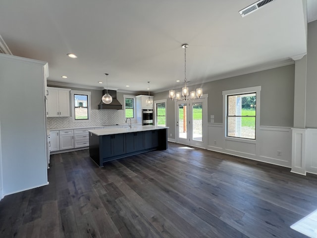 kitchen with pendant lighting, a center island with sink, dark hardwood / wood-style floors, and custom range hood