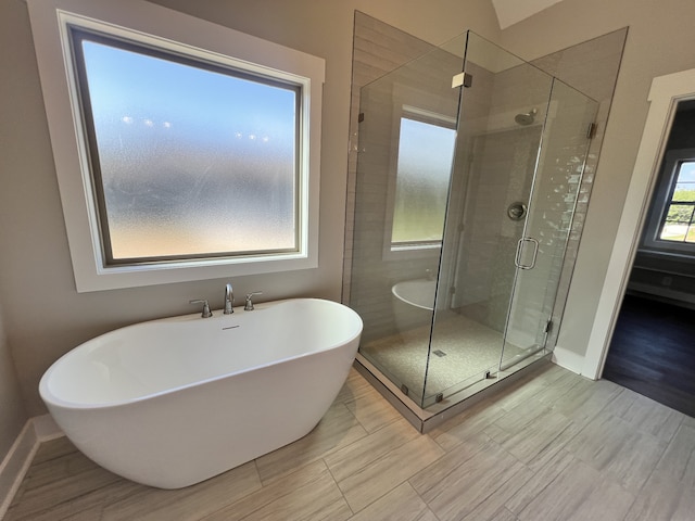 bathroom with shower with separate bathtub and wood-type flooring