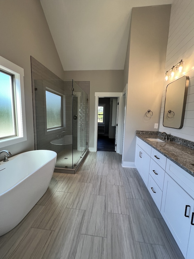 bathroom with vanity, separate shower and tub, and high vaulted ceiling