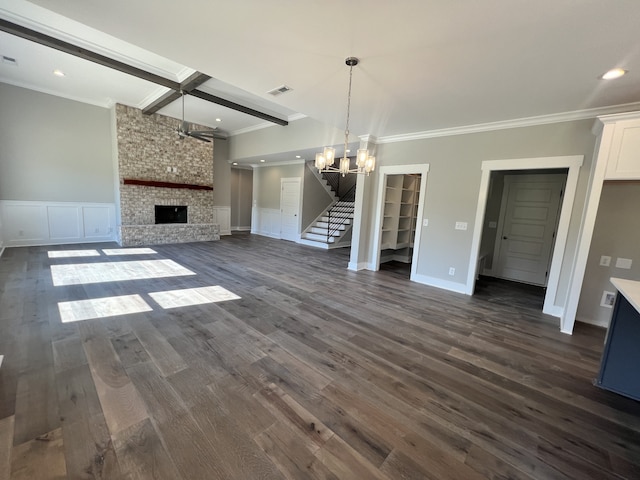 unfurnished living room with a fireplace, beamed ceiling, crown molding, an inviting chandelier, and dark hardwood / wood-style floors