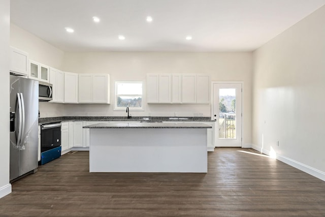 kitchen with stainless steel appliances, a kitchen island, white cabinetry, and a healthy amount of sunlight