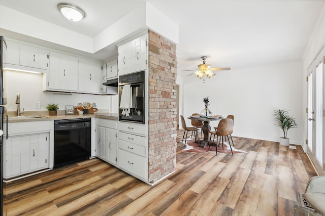 kitchen featuring wood-type flooring, sink, white cabinetry, black appliances, and ceiling fan