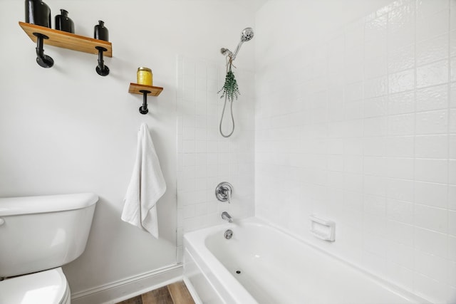 bathroom featuring wood-type flooring, tiled shower / bath, and toilet