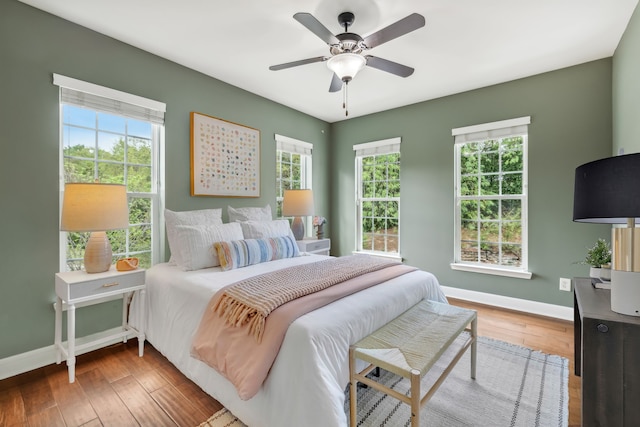 bedroom featuring multiple windows, wood-type flooring, and ceiling fan