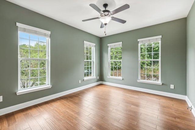 empty room with ceiling fan, hardwood / wood-style flooring, and a wealth of natural light