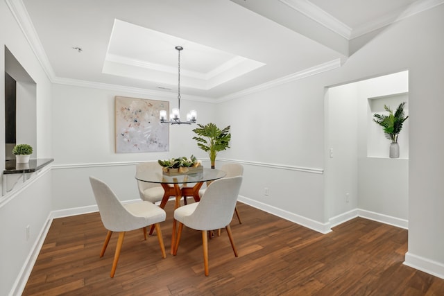 dining room with ornamental molding, dark wood-type flooring, a chandelier, and a tray ceiling