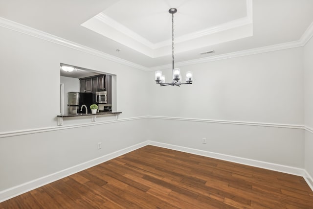 unfurnished room with an inviting chandelier, a raised ceiling, dark hardwood / wood-style floors, and ornamental molding