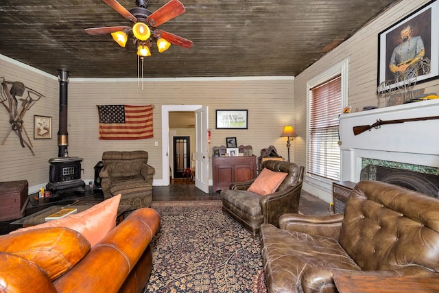 living room with ornamental molding, a wood stove, and ceiling fan