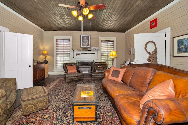 living room with ceiling fan, wooden walls, and plenty of natural light