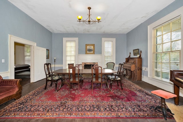 dining space featuring plenty of natural light, dark wood-type flooring, and a notable chandelier