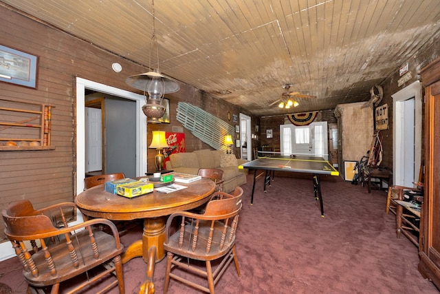 dining area with carpet flooring, wooden walls, and ceiling fan