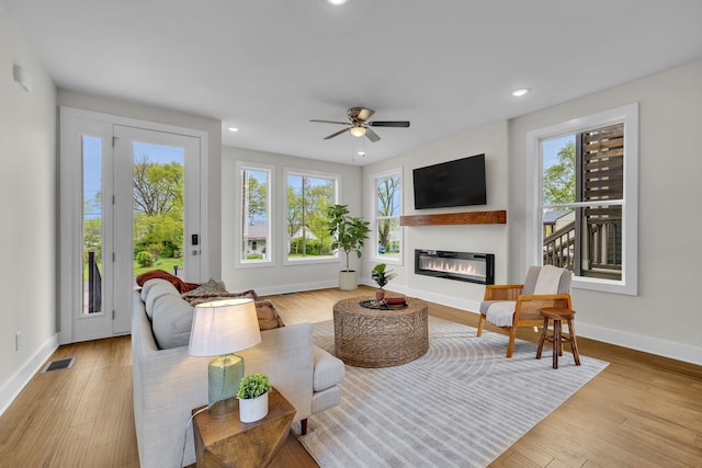 living room featuring a wealth of natural light, ceiling fan, and light wood-type flooring