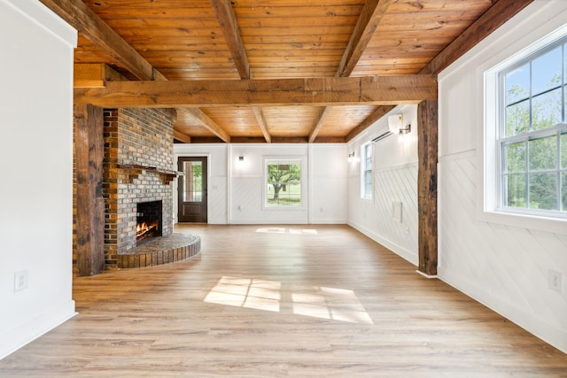 unfurnished living room featuring a brick fireplace, a wealth of natural light, light hardwood / wood-style floors, and wooden ceiling