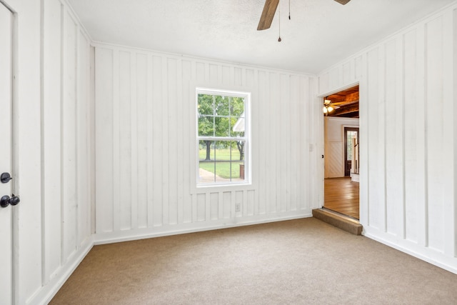 carpeted spare room featuring ceiling fan and a textured ceiling