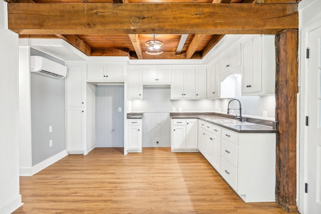 kitchen featuring light hardwood / wood-style flooring, white cabinets, beamed ceiling, and sink