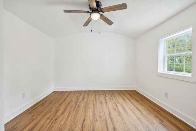 unfurnished room featuring a textured ceiling, light hardwood / wood-style floors, vaulted ceiling, and ceiling fan