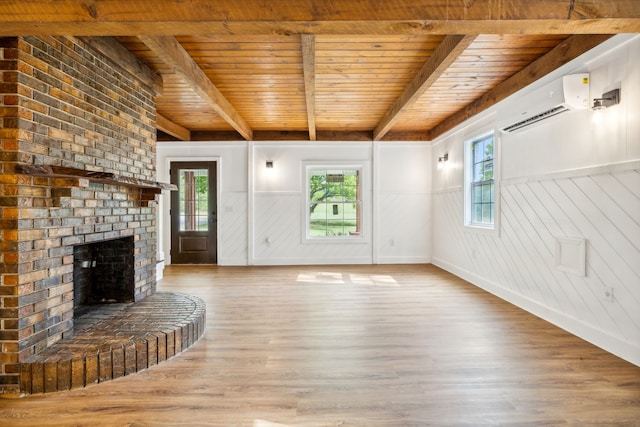 unfurnished living room featuring wood-type flooring, plenty of natural light, and a wall mounted AC