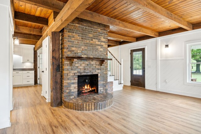 unfurnished living room featuring light wood-type flooring, beam ceiling, wood ceiling, and a fireplace