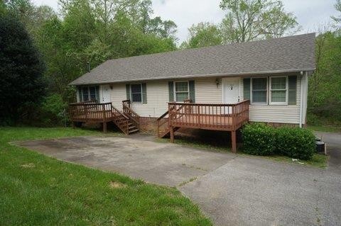 ranch-style home with a deck and a front lawn