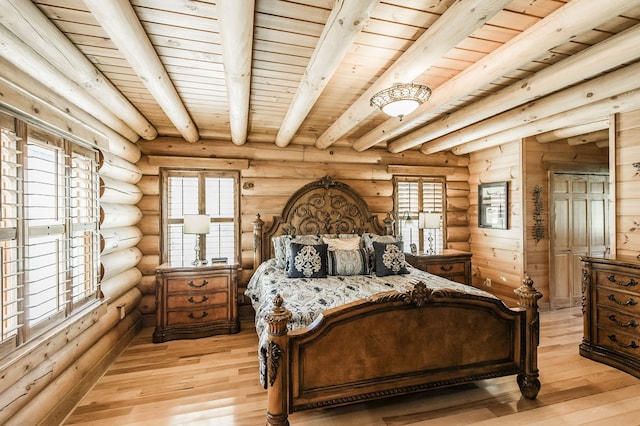 bedroom featuring light hardwood / wood-style floors, beamed ceiling, and log walls