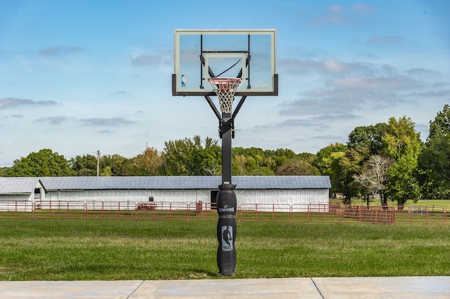 view of sport court with a rural view and a lawn