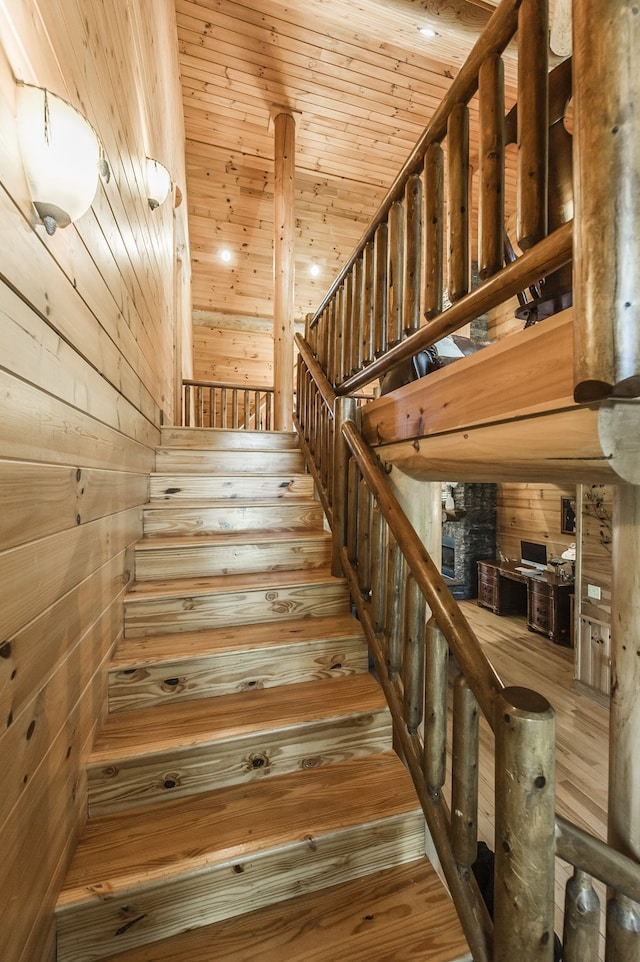 stairs featuring wood-type flooring, wooden walls, and wooden ceiling