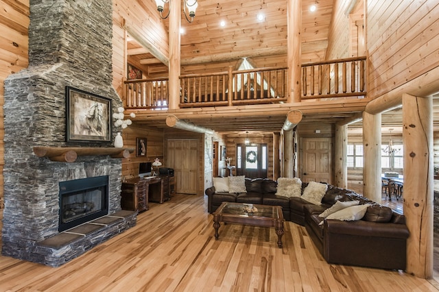 living room featuring wood ceiling, wood-type flooring, high vaulted ceiling, wooden walls, and a stone fireplace