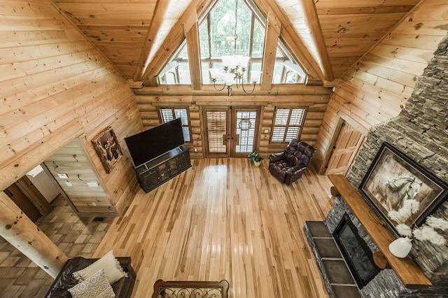 unfurnished living room featuring wood ceiling, high vaulted ceiling, hardwood / wood-style flooring, and a stone fireplace