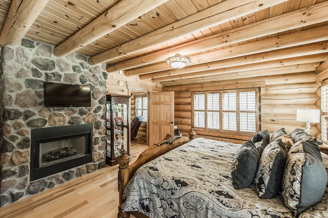 bedroom with wood ceiling, a stone fireplace, beam ceiling, and hardwood / wood-style floors