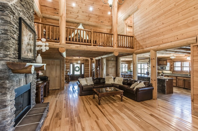 living room featuring sink, high vaulted ceiling, a fireplace, wooden ceiling, and light wood-type flooring