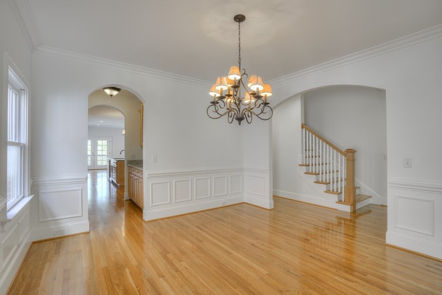 spare room featuring ornamental molding, light hardwood / wood-style floors, and an inviting chandelier