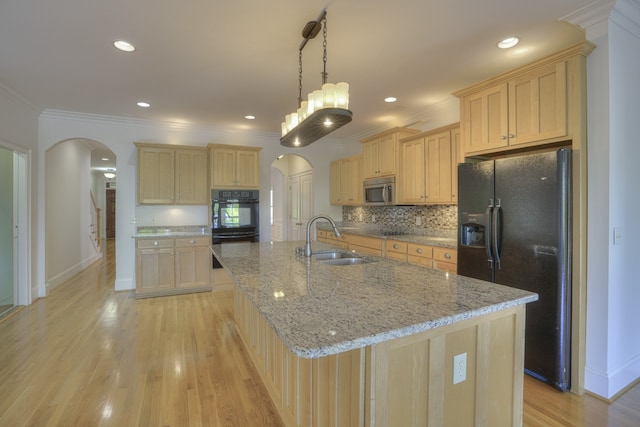 kitchen with light hardwood / wood-style flooring, black appliances, and a kitchen island with sink