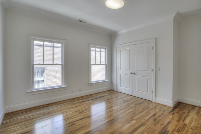 unfurnished bedroom featuring a closet, light wood-type flooring, and ornamental molding