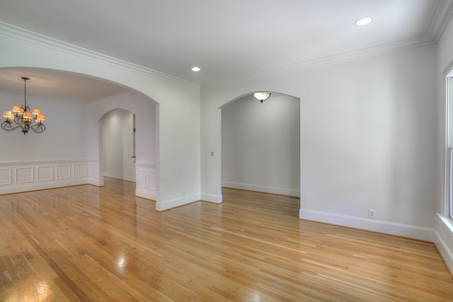 unfurnished room with a notable chandelier, light wood-type flooring, and crown molding