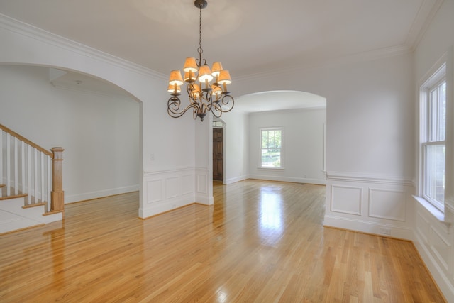 empty room featuring an inviting chandelier, crown molding, and light hardwood / wood-style floors